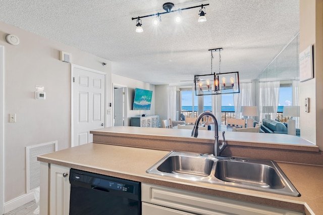 kitchen featuring dishwasher, rail lighting, a textured ceiling, sink, and an inviting chandelier