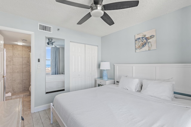 bedroom with ceiling fan, a closet, ensuite bath, and a textured ceiling