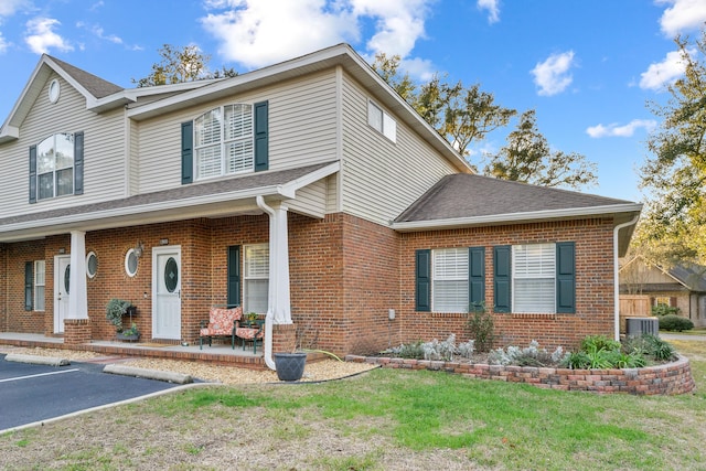 view of front facade with a porch, central AC, and a front lawn