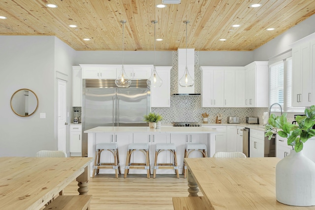 kitchen with stainless steel built in fridge, wooden ceiling, a kitchen island, wall chimney range hood, and pendant lighting