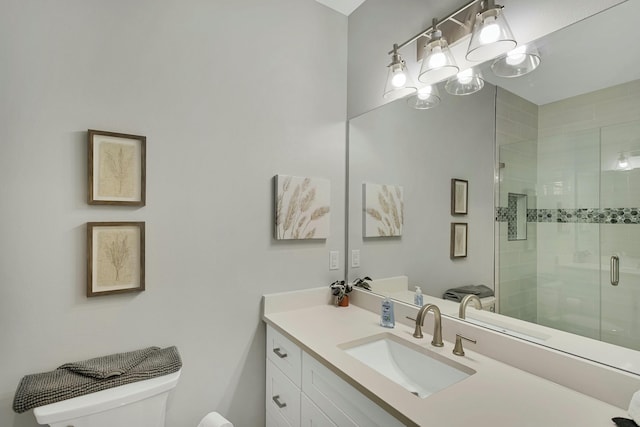 bathroom featuring a shower with door, vanity, and toilet