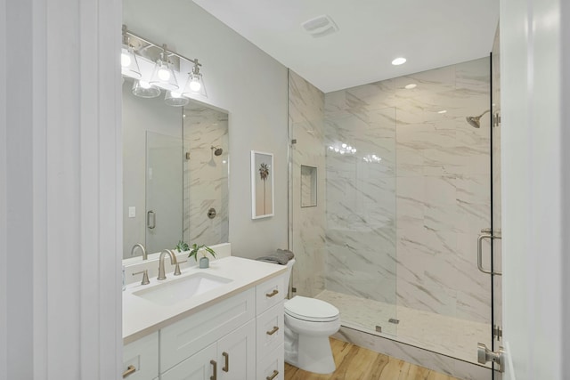 bathroom featuring toilet, vanity, a shower with shower door, and hardwood / wood-style flooring