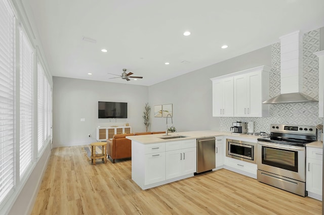 kitchen with stainless steel appliances, sink, light wood-type flooring, and kitchen peninsula