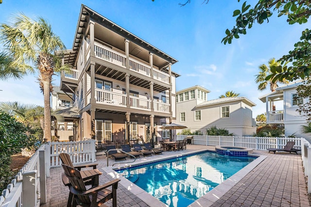 back of house featuring a pool with hot tub, a patio area, and a balcony