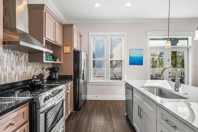 kitchen with pendant lighting, sink, crown molding, appliances with stainless steel finishes, and wall chimney exhaust hood