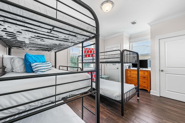 bedroom featuring crown molding, dark hardwood / wood-style flooring, and multiple windows