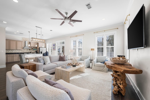 living room with ornamental molding, dark wood-type flooring, and ceiling fan