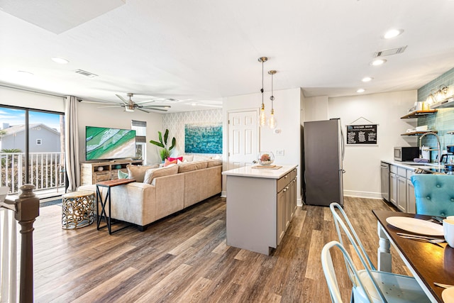 kitchen with ceiling fan, sink, decorative light fixtures, dark wood-type flooring, and stainless steel appliances