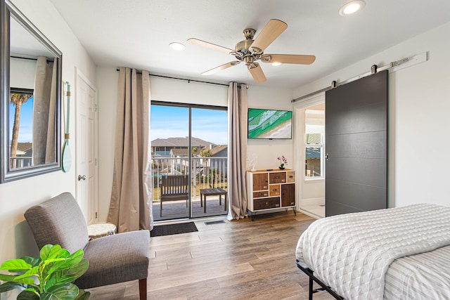 bedroom featuring ceiling fan, access to exterior, hardwood / wood-style floors, and a barn door