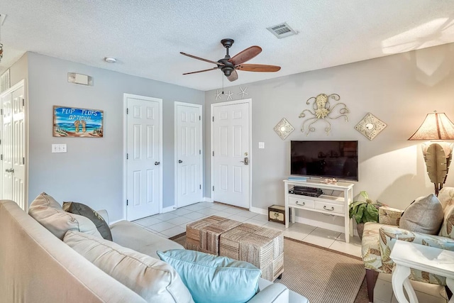 living room with a textured ceiling, ceiling fan, and light tile patterned floors