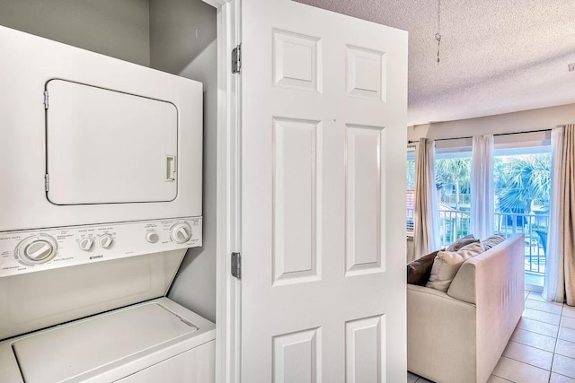 laundry room with stacked washing maching and dryer, light tile patterned floors, and a textured ceiling