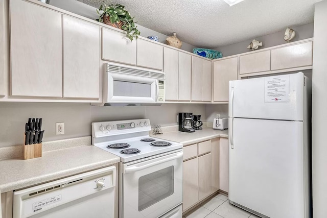 kitchen with white appliances, light tile patterned flooring, and a textured ceiling