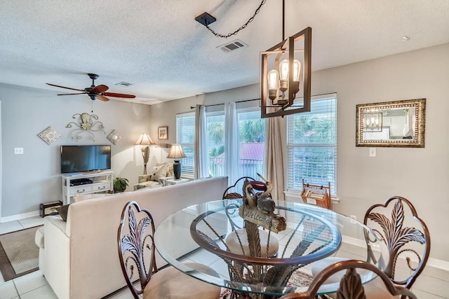 tiled dining area with a textured ceiling and ceiling fan with notable chandelier