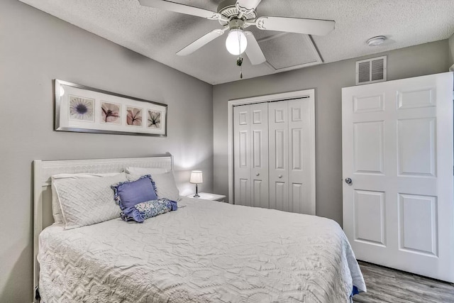 bedroom with light hardwood / wood-style floors, a closet, ceiling fan, and a textured ceiling