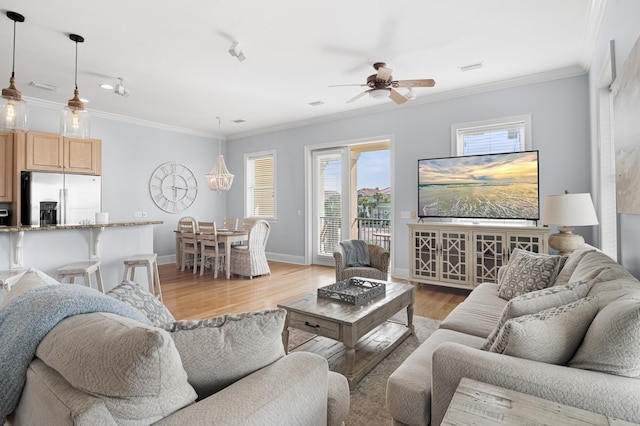 living room with crown molding, ceiling fan with notable chandelier, and light wood-type flooring