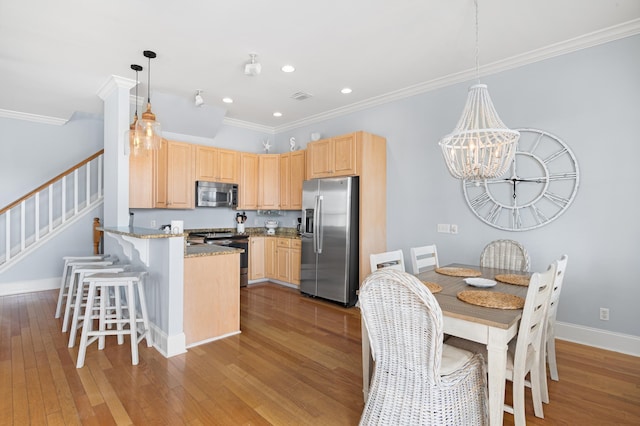 kitchen with decorative light fixtures, light hardwood / wood-style flooring, light brown cabinets, stainless steel appliances, and light stone countertops