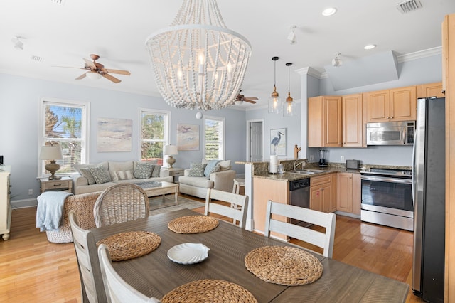 dining area with ornamental molding, sink, ceiling fan with notable chandelier, and light hardwood / wood-style flooring