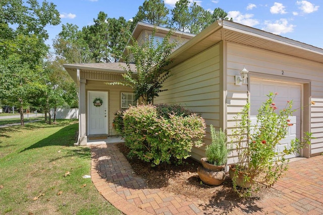 doorway to property featuring a garage and a lawn