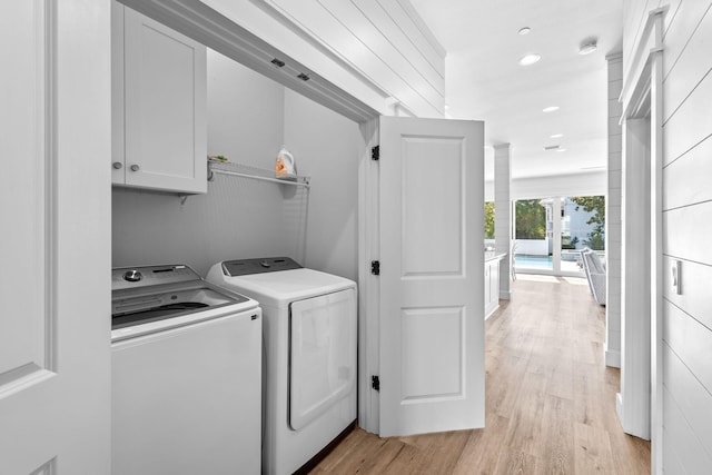 washroom with independent washer and dryer, cabinets, and light hardwood / wood-style flooring