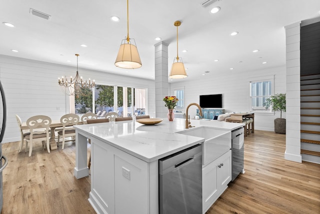 kitchen with light stone countertops, dishwasher, hanging light fixtures, an island with sink, and white cabinets