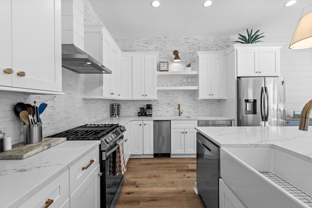 kitchen with appliances with stainless steel finishes, wall chimney exhaust hood, tasteful backsplash, and white cabinetry