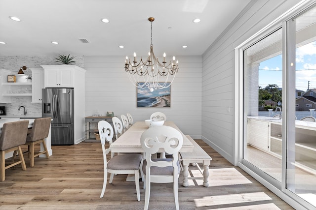 dining room with light hardwood / wood-style flooring and a chandelier