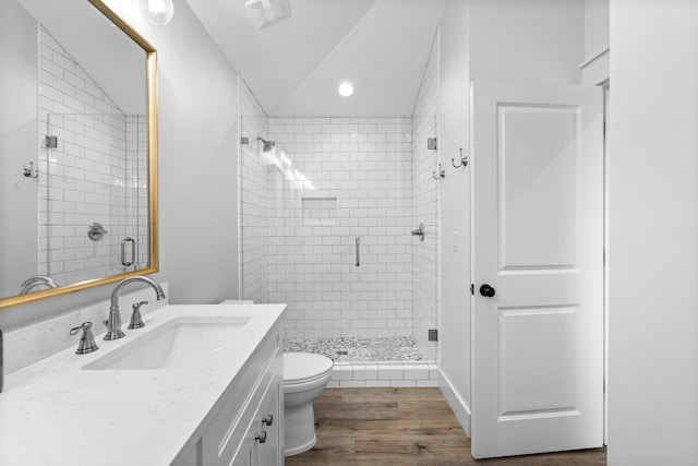 bathroom featuring toilet, vanity, a shower with shower door, hardwood / wood-style flooring, and lofted ceiling