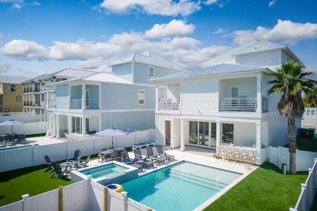 back of house with a yard, a balcony, a pool with hot tub, a patio, and a bar