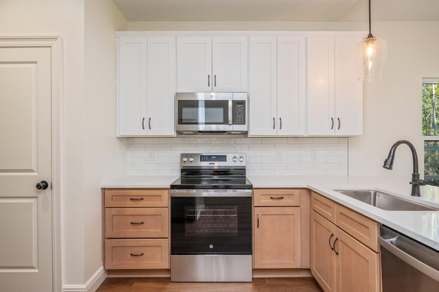 kitchen with hanging light fixtures, appliances with stainless steel finishes, sink, and tasteful backsplash