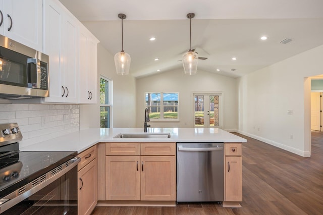 kitchen featuring kitchen peninsula, stainless steel appliances, light brown cabinets, lofted ceiling, and sink