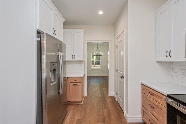 kitchen featuring white cabinetry, an inviting chandelier, tasteful backsplash, stainless steel fridge with ice dispenser, and hardwood / wood-style flooring