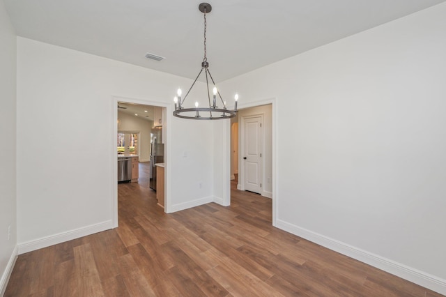 unfurnished dining area featuring dark hardwood / wood-style floors, lofted ceiling, and a notable chandelier