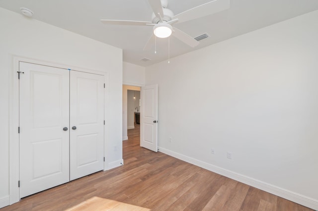 unfurnished bedroom featuring ceiling fan, a closet, and light wood-type flooring