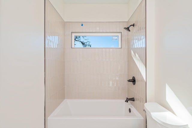 bathroom featuring toilet and tiled shower / bath