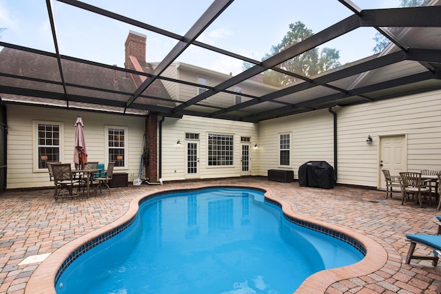 view of pool featuring a grill, glass enclosure, and a patio area