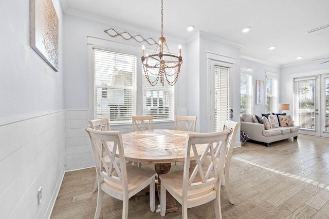 dining room with an inviting chandelier, a wealth of natural light, light hardwood / wood-style floors, and crown molding