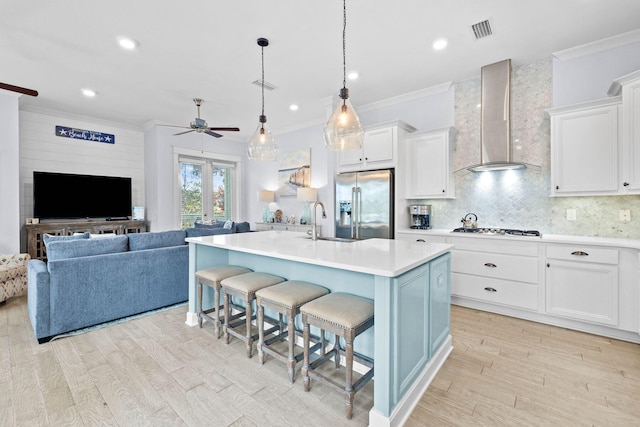 kitchen featuring stainless steel fridge with ice dispenser, a center island with sink, wall chimney exhaust hood, and white cabinets