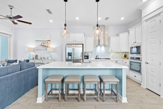 kitchen with stainless steel appliances, a breakfast bar, a spacious island, white cabinets, and wall chimney range hood