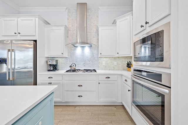 kitchen featuring stainless steel appliances, white cabinets, wall chimney exhaust hood, ornamental molding, and decorative backsplash