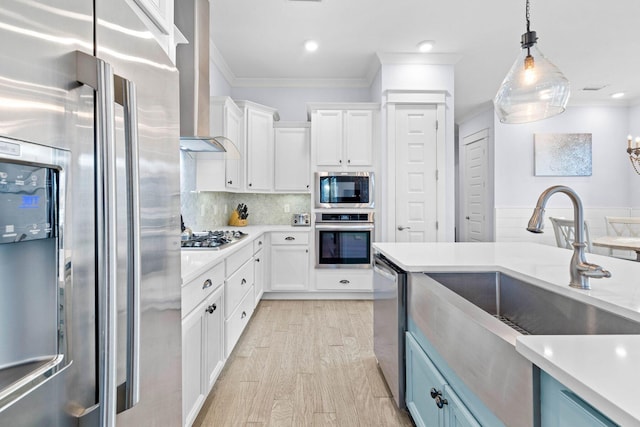 kitchen featuring stainless steel appliances, white cabinetry, pendant lighting, and wall chimney exhaust hood