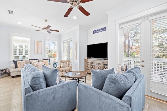 living room with light hardwood / wood-style floors, ceiling fan, a healthy amount of sunlight, and crown molding