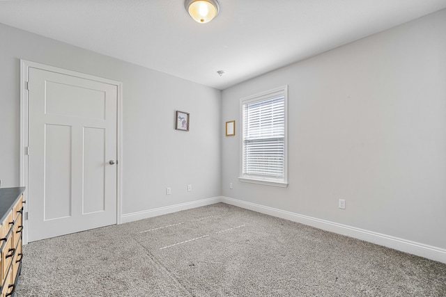 spare room featuring carpet and baseboards