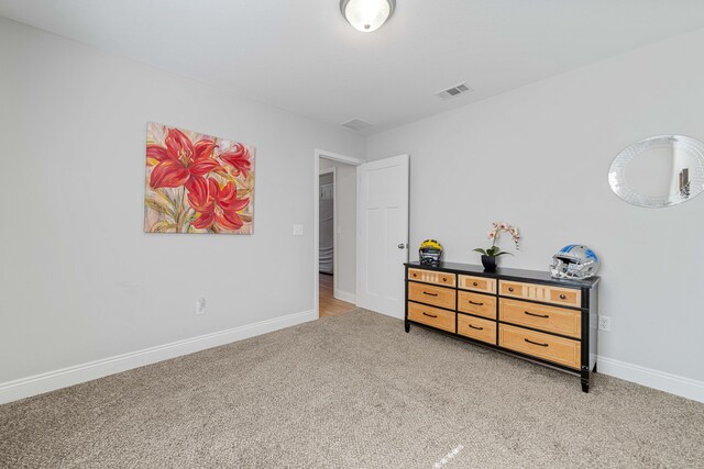 bedroom with baseboards, visible vents, and light colored carpet