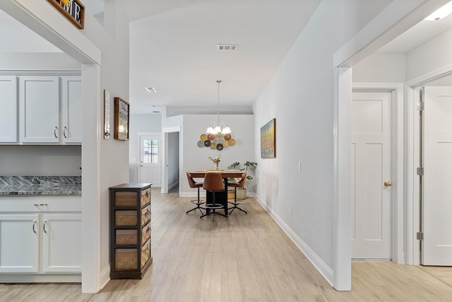 interior space with baseboards, a notable chandelier, visible vents, and light wood-style floors