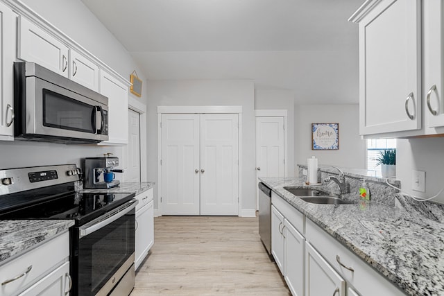 kitchen with stainless steel appliances, white cabinets, a sink, and light stone counters