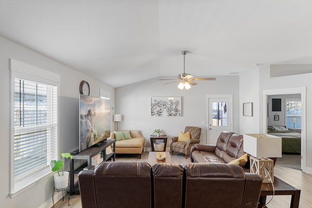 living area with vaulted ceiling, baseboards, plenty of natural light, and light wood finished floors