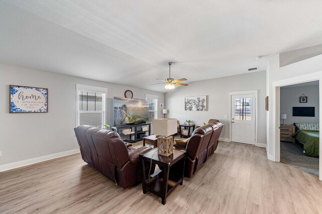 living room with lofted ceiling, light wood-style flooring, visible vents, and baseboards