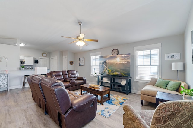 living room with light wood-type flooring, plenty of natural light, lofted ceiling, and baseboards