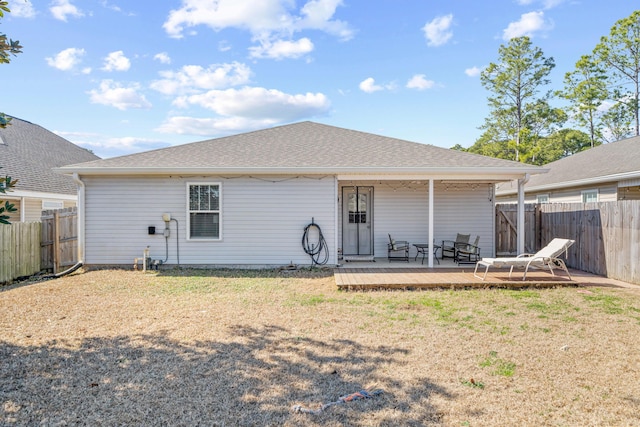 back of property featuring roof with shingles, a lawn, a fenced backyard, and a wooden deck