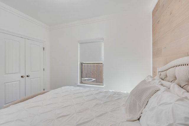 bedroom featuring a closet, wooden walls, and ornamental molding